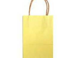Желтый бумажный пакет с кручеными бумажными ручками.